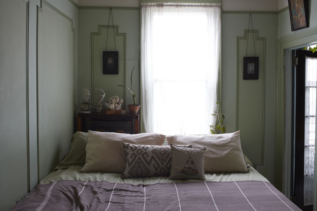 The small bedroom is painted a pale blue-green. The bed takes up a large amount of space.
