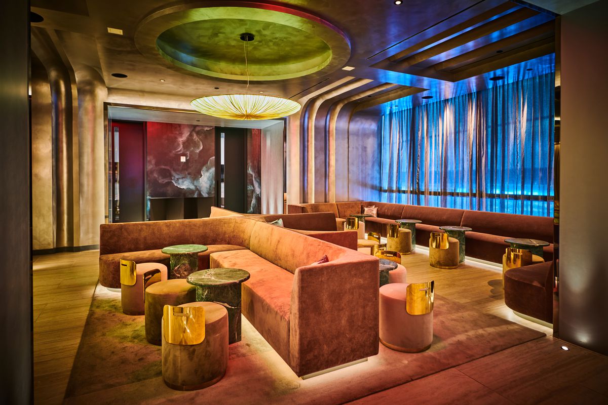 A high-ceilinged lounge with gold tones and plush seating.