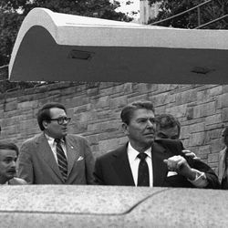 U.S. President Ronald Reagan looks to his left and holds up his left arm as a secret service agent places a hand on his shoulder and pushes the President into his limousine after he was shot leaving a Washington hotel, Monday, March 30, 1981.