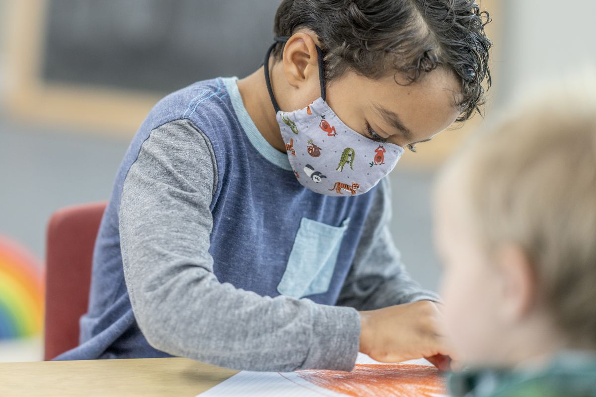 A child in a mask at a day care colors