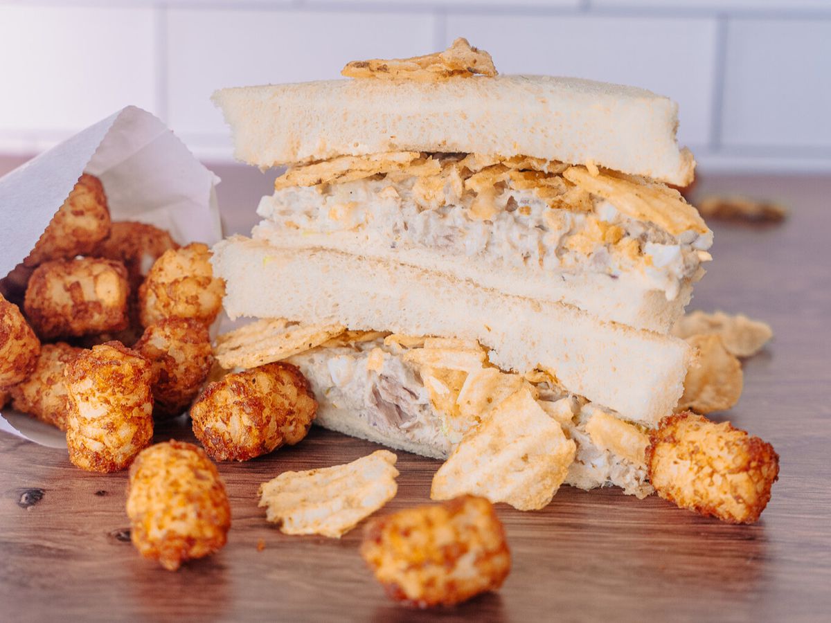 Stuffed Belly’s tuna sandwich stuffed with crispy potato chips with a side of tater tots.