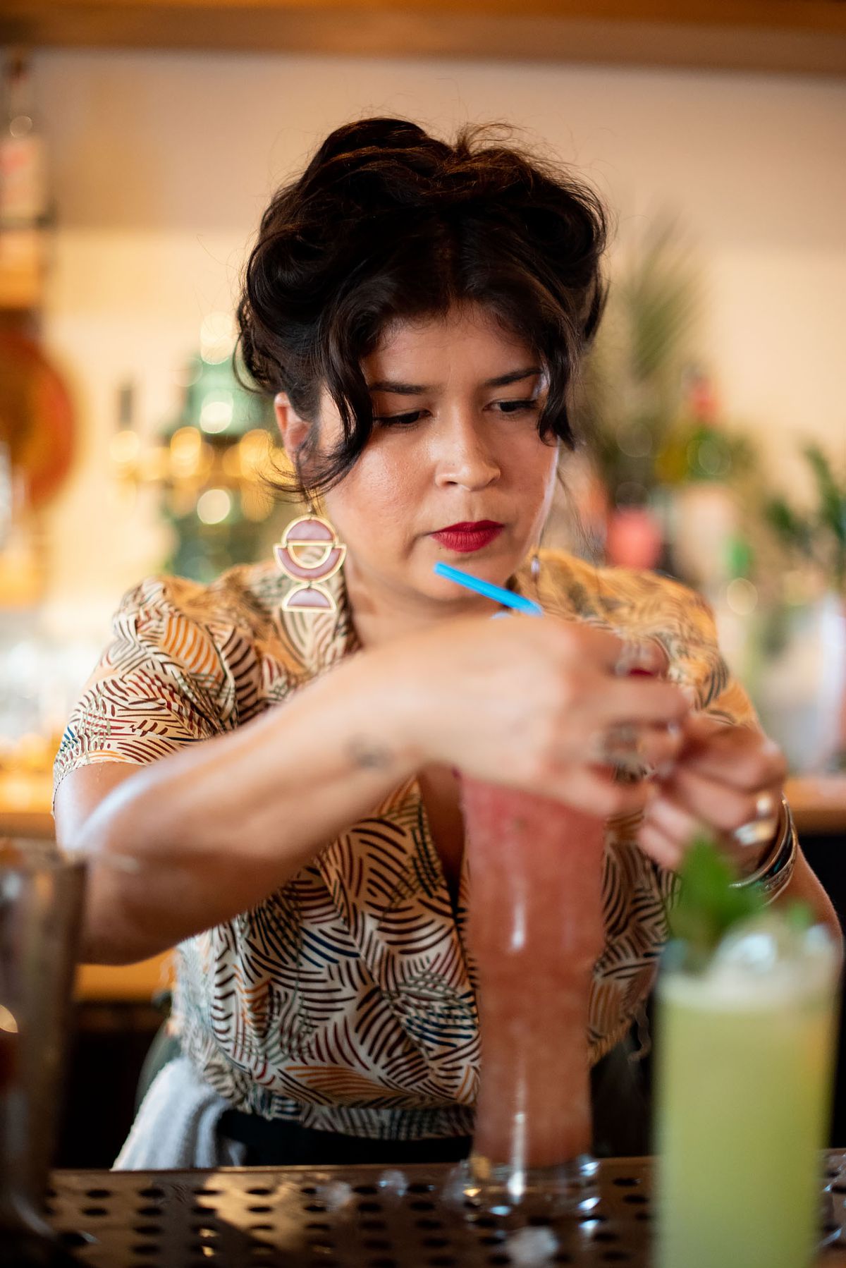 Bartender garnishes a colorful cocktail.