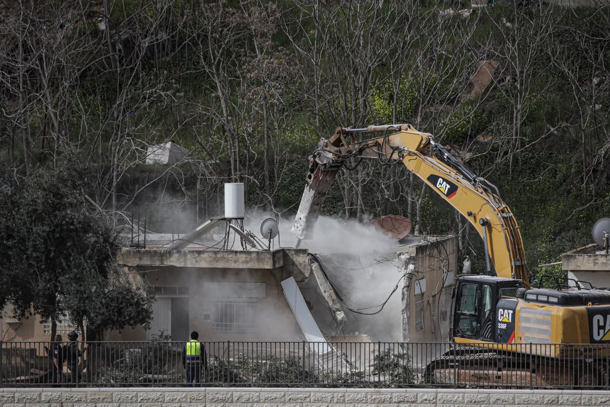 A bulldozer destroys a home.