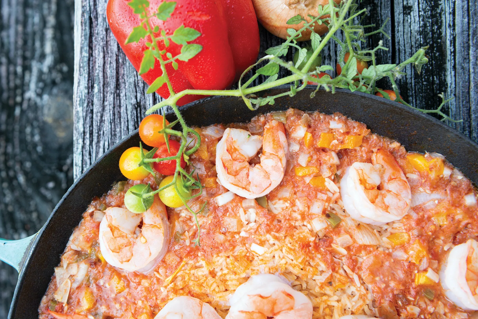 Effie's Shrimp creole in a cast iron skillet next to a garnish and a red bell pepper