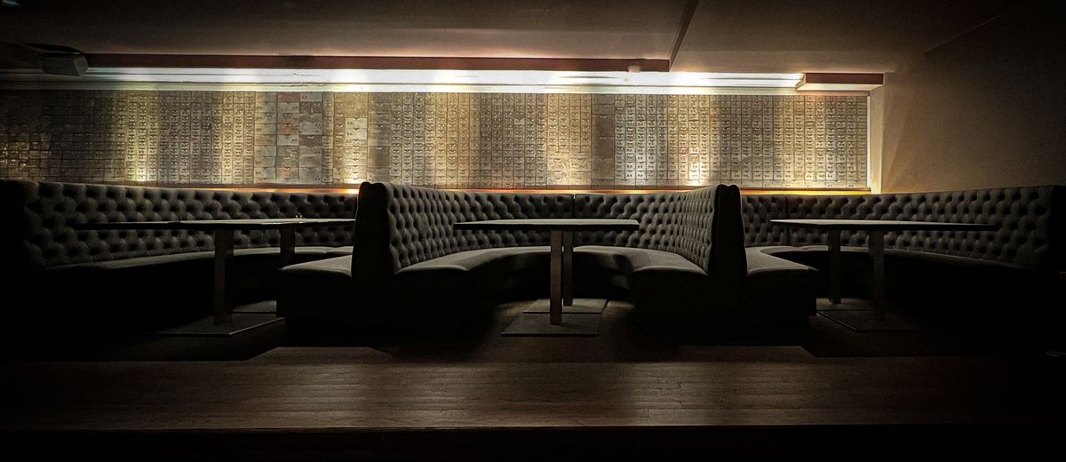 A low-lit bank vault with black u-shaped booths.