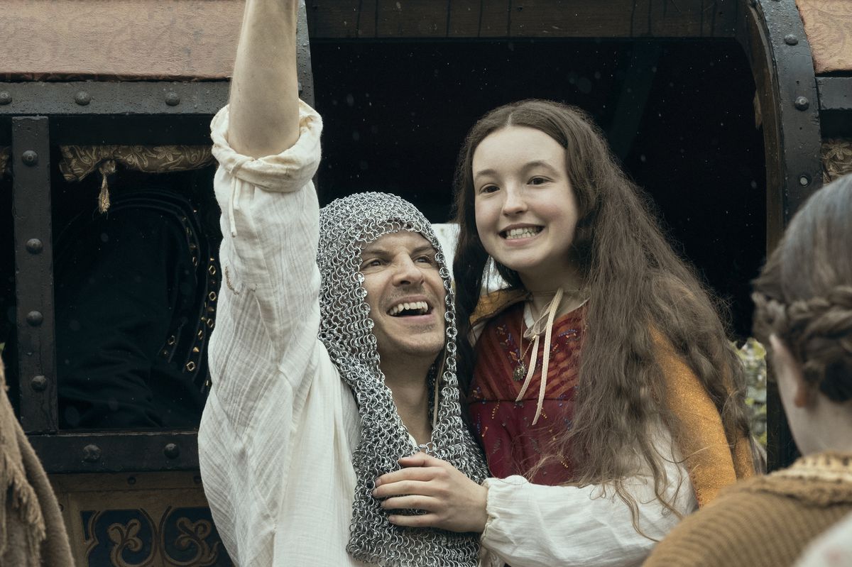 A man in chain mail holds up a young teenage girl 