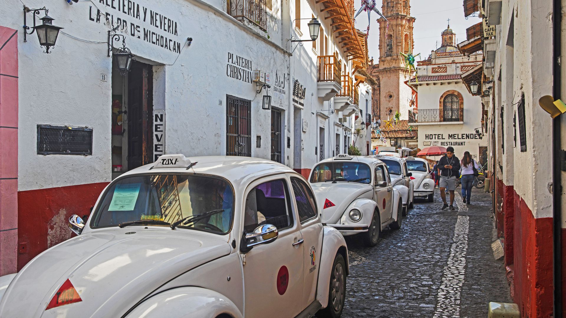 White Volkswagen Beetle taxis in narrow street in the colonial city centre of Taxco de Alarc—n, Guerrero, Mexico