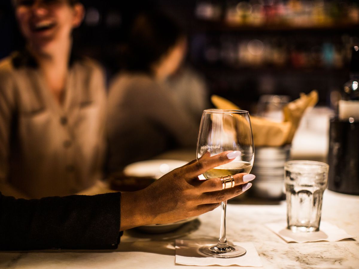 A person grabs a glass of wine at a bar.