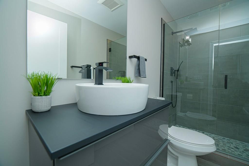 A bathroom with a basin sink next to a toilet next to a glass-door shower. 