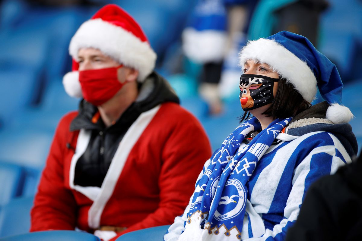 Fans dressed as Father Christmas and wearing a face mask or covering due to the COVID-19 pandemic, sit socially distanced as they wait for kick off in the English Premier League