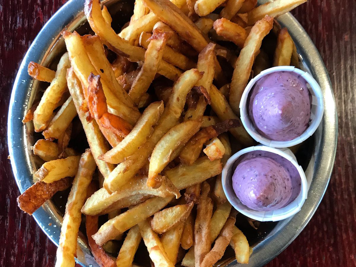 From above, a plate of french fries with bright purple dipping sauce.