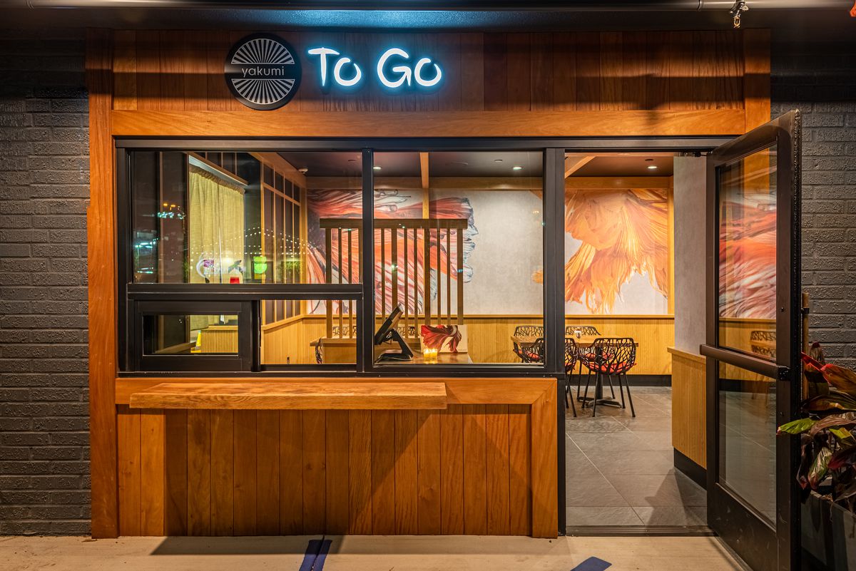 A takeout/to-go window wrapped in wood for a new sushi restaurant, at night.