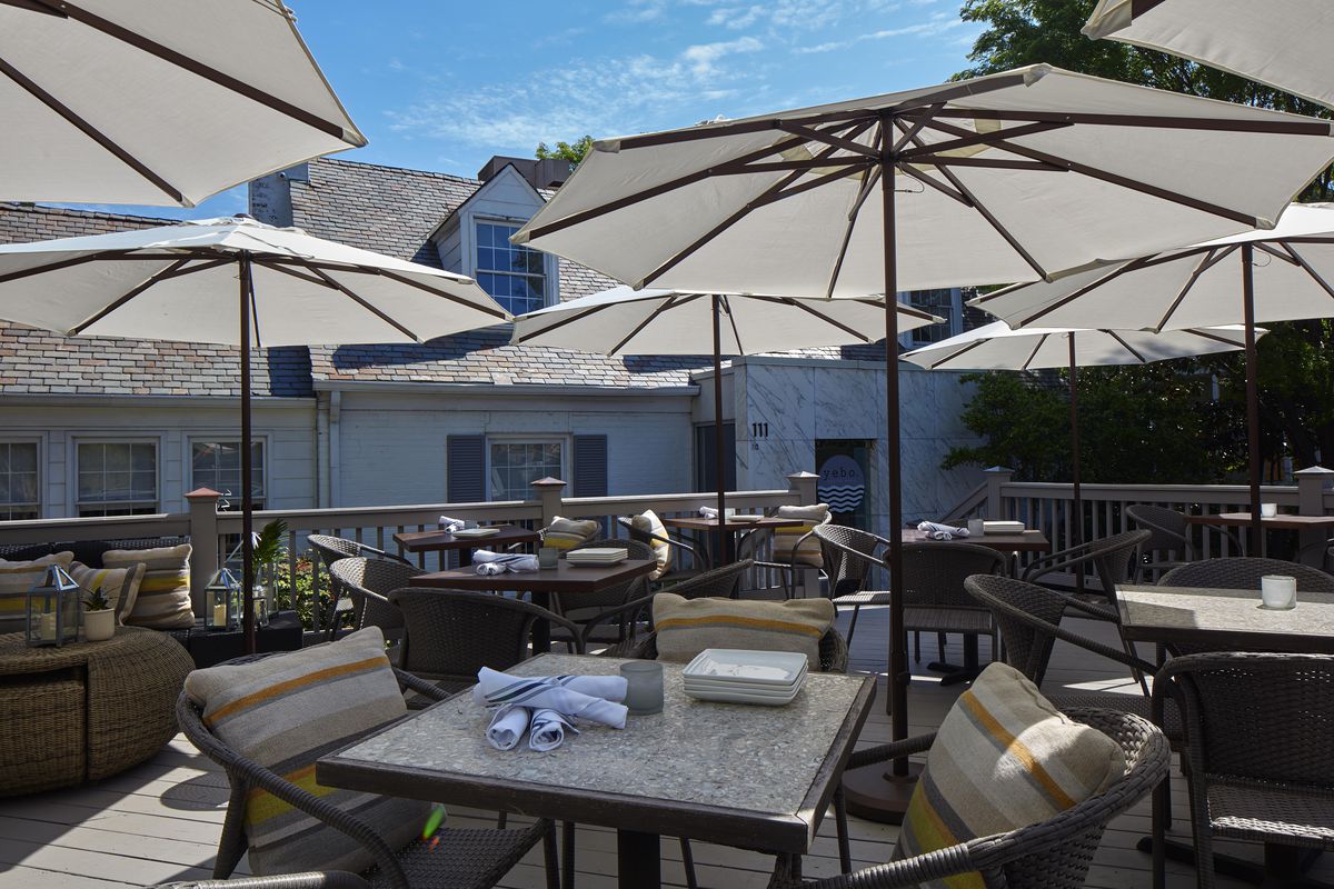 The outdoor patio at the current location of Yebo Beach Haus with tables and umbrellas