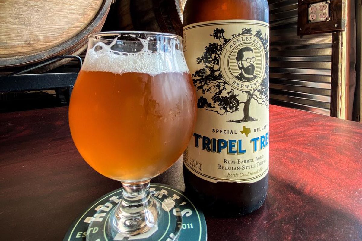 A round glass of amber beer next to a bottle of beer with a label that reads “Tripel.”