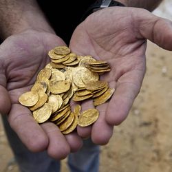 Kobi Sharvit of The Israel Antiquities Authority Fatimid period gold coins that were found in the seabed in the Mediterranean Sea near the port of Caesarea National Park in Caesarea, Israel, Wednesday, Feb. 18, 2015. A group of amateur Israeli divers have stumbled upon the largest collection of medieval gold coins ever found in the country, dating back to the 11th century and likely from a shipwreck in the Mediterranean Sea. 