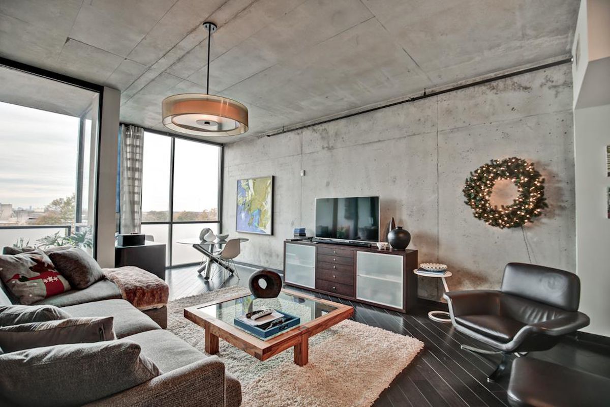 Concrete walls and ceiling with dark hardwood floors, modern furniture and large windows.