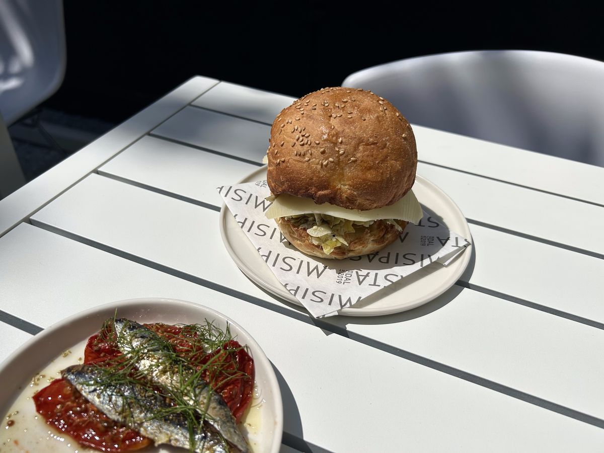 A sandwich and smoked anchovies share a table.