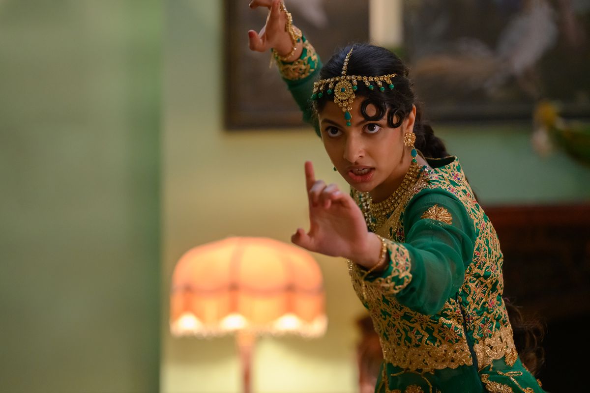 ریا، یک دختر نوجوان پاکستانی با لباس سنتی رقص سبز و طلایی، دستانش را در حالت جنگی دراز کرده است.