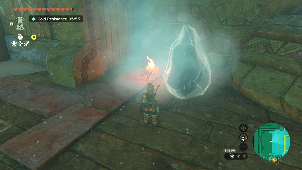 Link stands before an icy boulder radiating an aura of coldness. There is a small campfire to the left melting the ice.