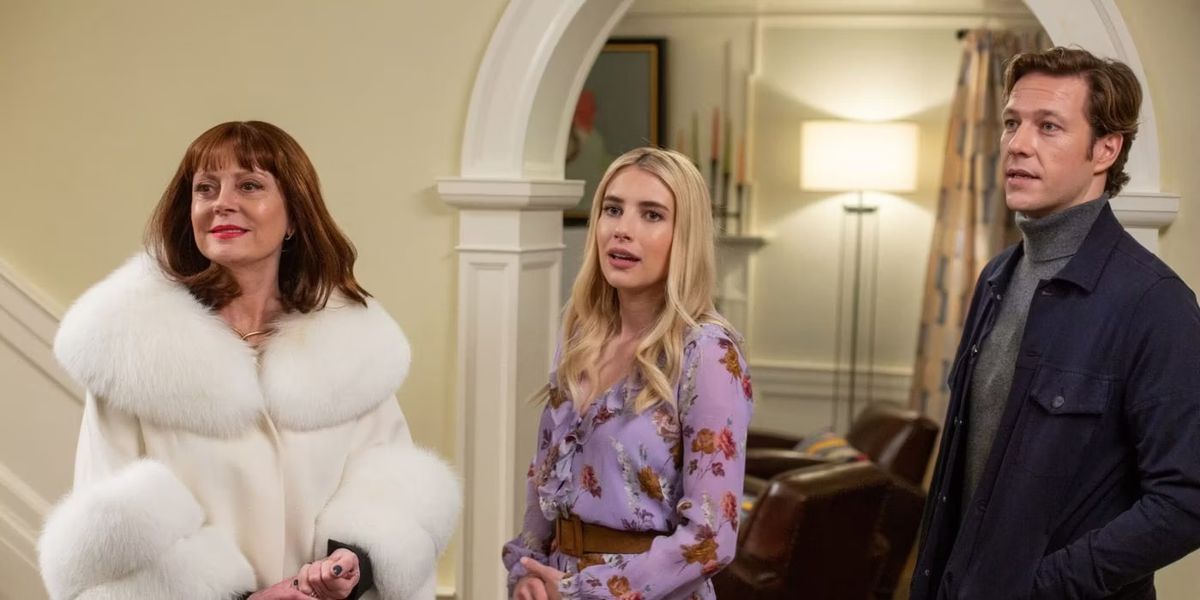 Susan Sarandon, Emma Roberts, and Luke Bracey stand next to each other in a house in Maybe I Do. Sarandon wears a puffy white fur coat.