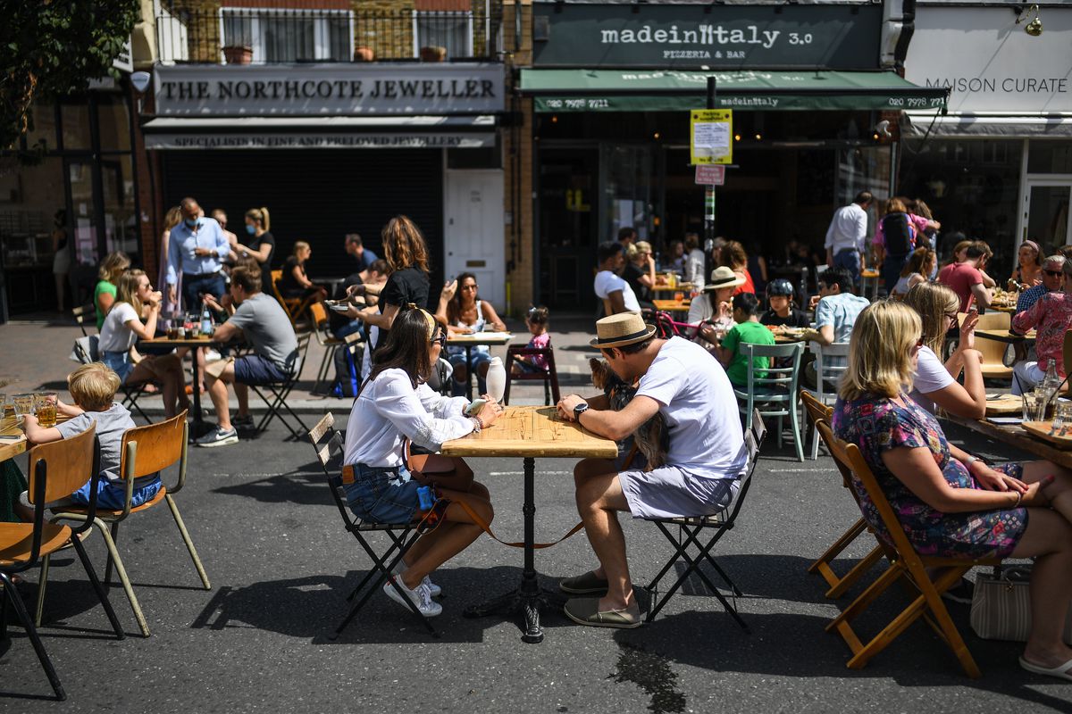 Diners sit outside at tables on a street in Clapham, London