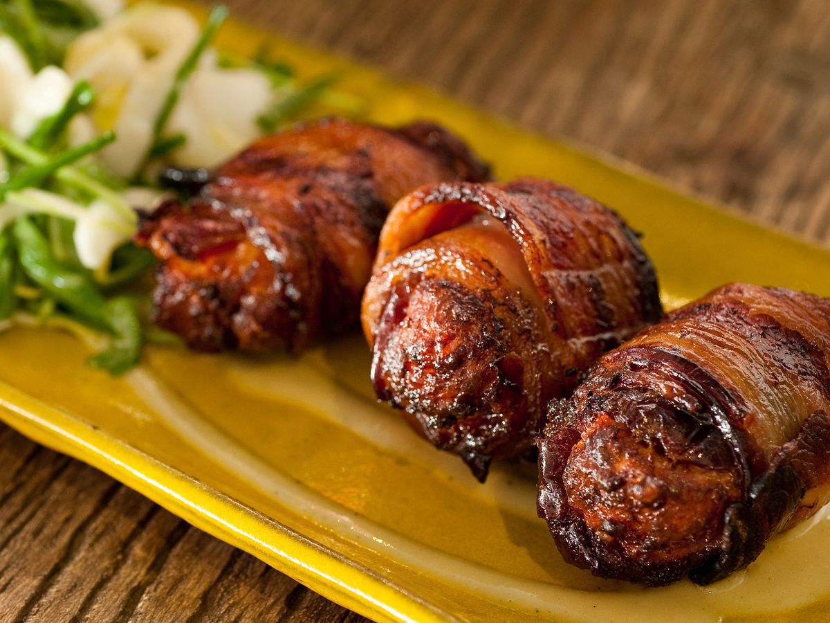 Bacon wrapped dates on yellow plate