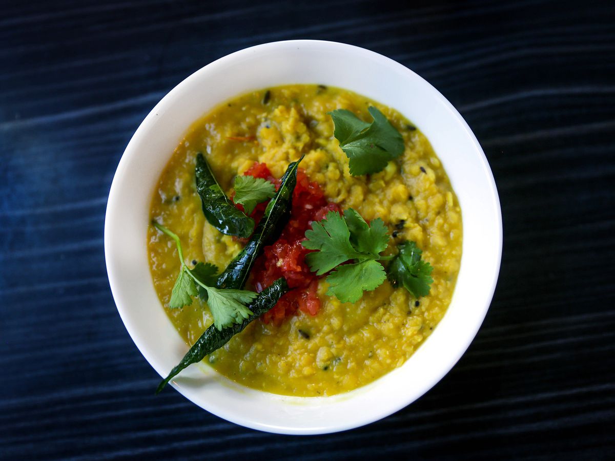 A fried curry leaf sits on a bowl of yellow-hued dal at Bhuna in Portland, Oregon.