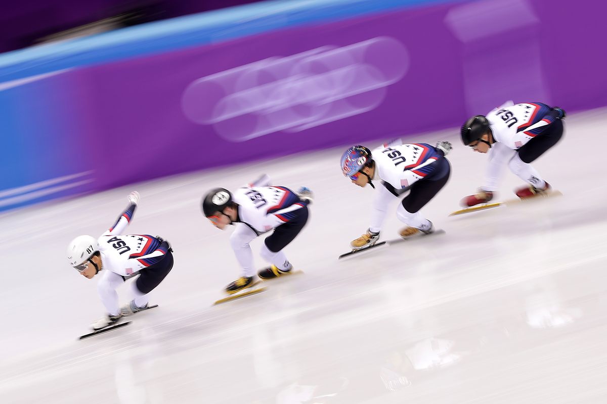 Four Olympic speed skaters in USA jerseys racing on the ice