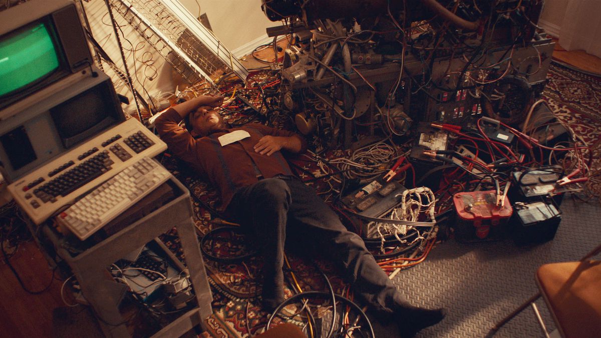 Middle-aged inventor Jabir (Payman Maadi) sprawls on his back on the floor with one arm flung over his head, surrounded by wires, jumper cables, car batteries, an ancient green-screen monitor and keyboard, and other old-school tech in Aporia