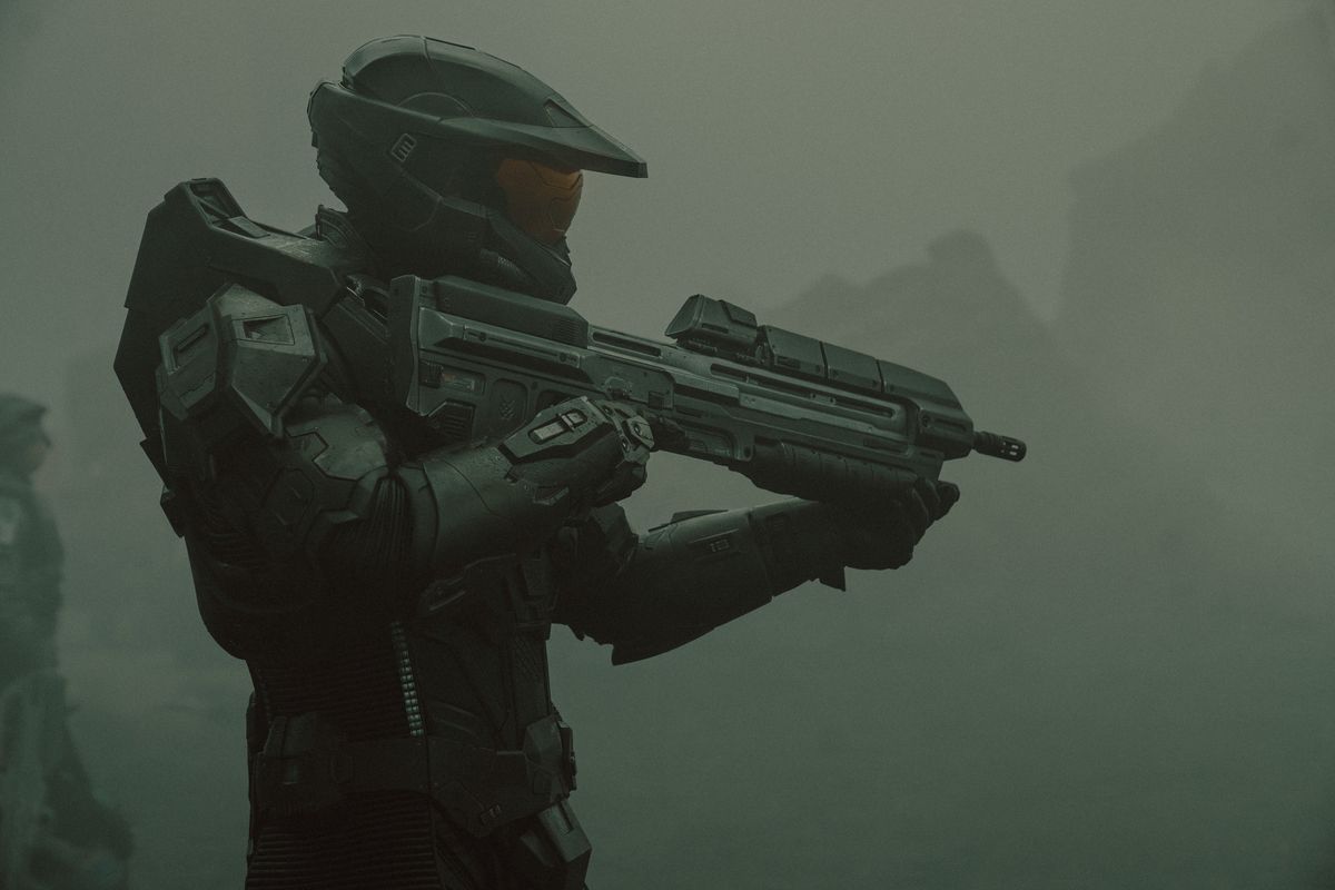 Master Chief (Pablo Schreiber) standing and holding his plasma rifle
