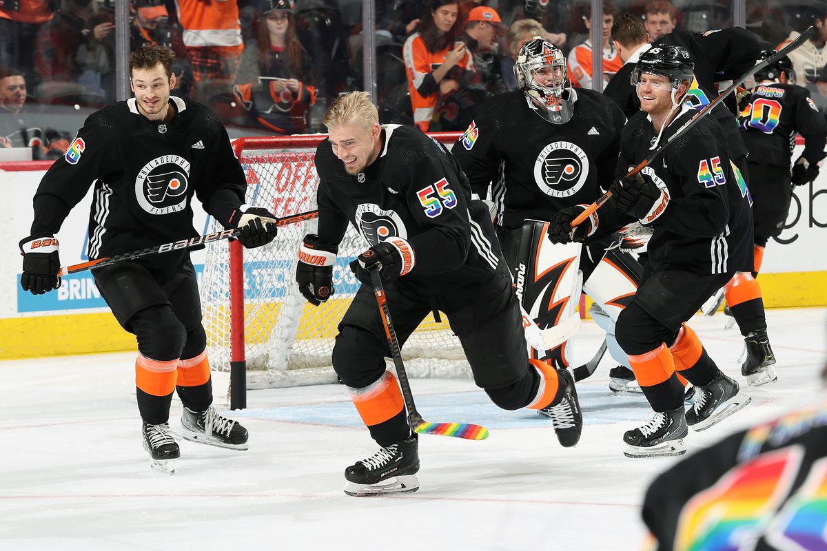A group of Flyers players all skating in warm-ups in front of the net, all of them wearing jerseys with pride-themed rainbow letters and nameplates
