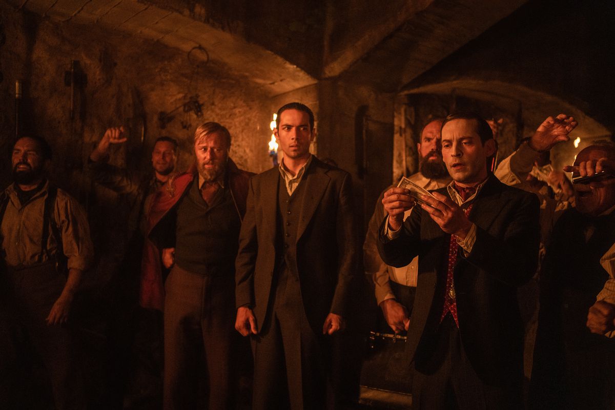 Manny looks on nervously as James McKay (played by Toby Maguire) incredulously holds up some money in his hands while the two stand in an ominous cellar surrounded by unsavory types in the film Babylon
