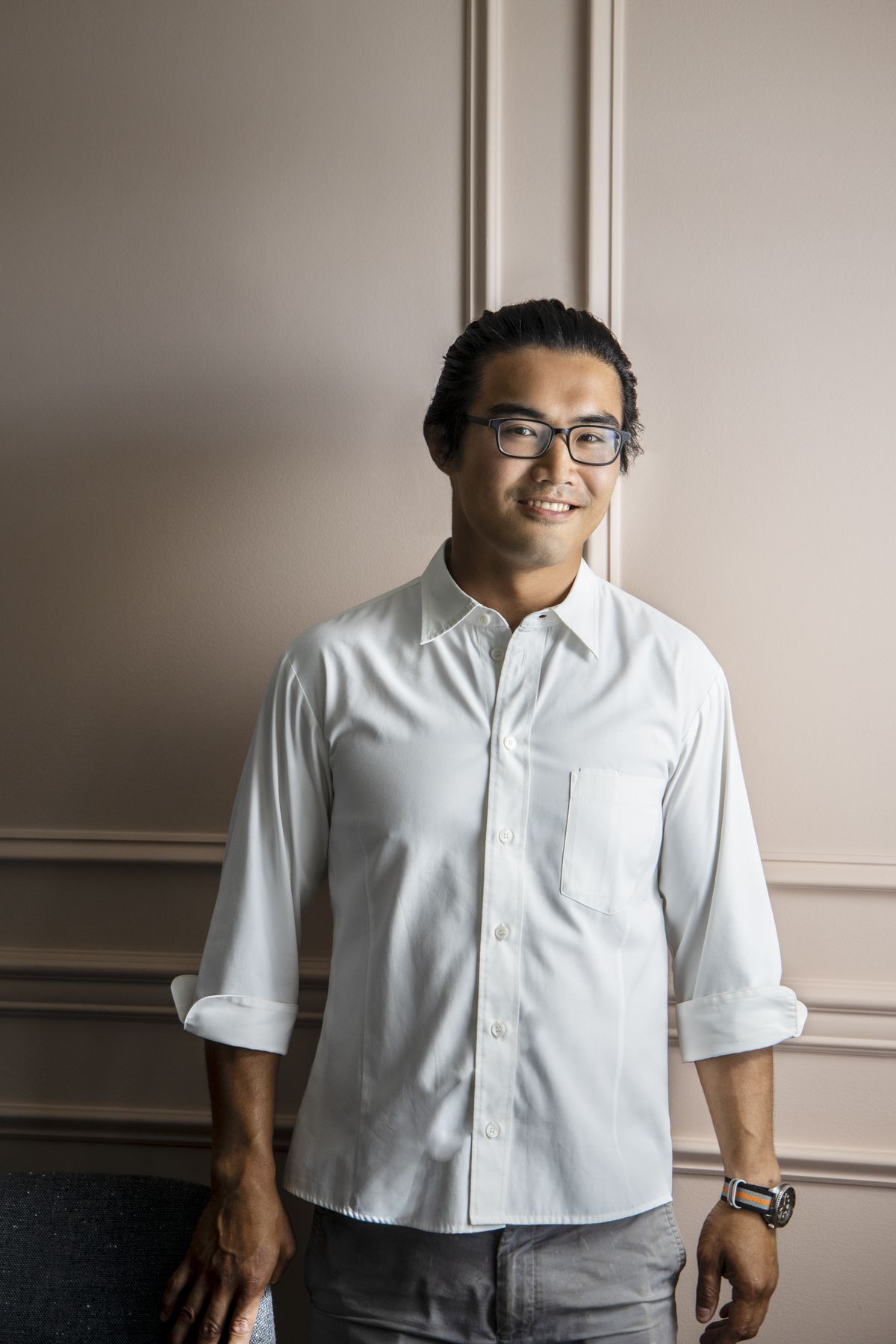 Chef Bin Lu poses for a portrait in a white button-down shirt.