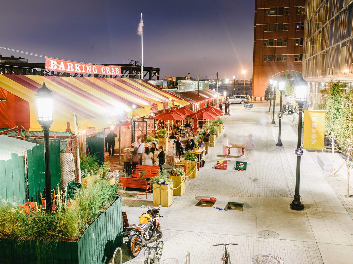 Outside view of the Barking Crab at night, featuring its distinctive red and yellow striped tent