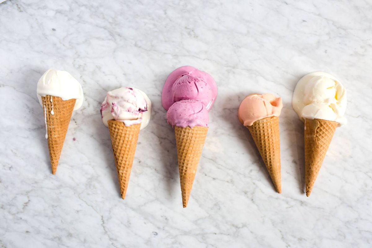 Five ice cream cones lay on a marble tabletop.