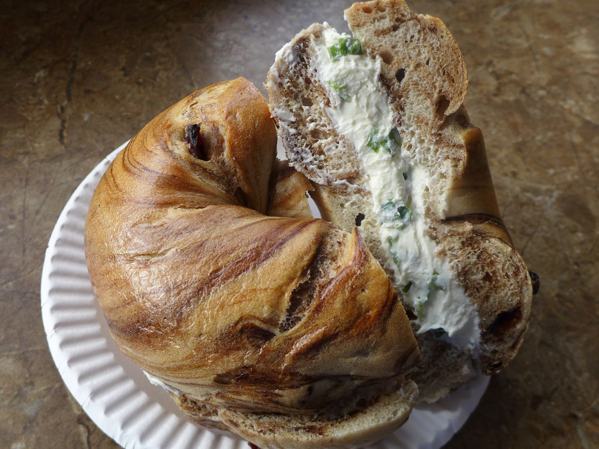 A cinnamon raisin bagel is cut in half with cream cheese at Forest Hills Bagel in Queens.