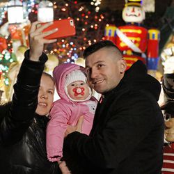 In this Dec. 14, 2016, photo, Tanya, Adriana and Vasyl Palinchak take a selfie in front of an elaborately-decorated home in the Dyker Heights neighborhood of the Brooklyn borough of New York. 