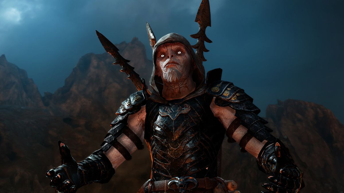 This screenshot from Middle-earth: Shadow of War shows a close-up of Zog, an orc necromancer. Zog’s body and arms are armored, but he wears a cloth hood on his head. Two spears are sticking out from behind his back, and his eyes glow an eerie white.