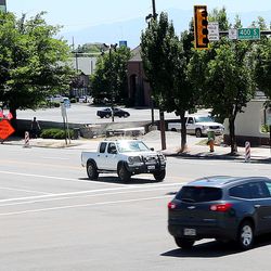 A pedestrian crosses the street as vehicles make left turns in Salt Lake City on Monday, June 25, 2018.