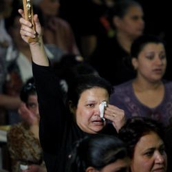 An Egyptian Christian holds a cross during a funeral service at the Saint Mark Coptic cathedral in Cairo, Egypt, Sunday, April 7, 2013. Several Egyptians including 4 Christians and a Muslim were killed in sectarian clashes before dawn in Qalubiya, just outside of Cairo on Saturday, April 6, 2013. 