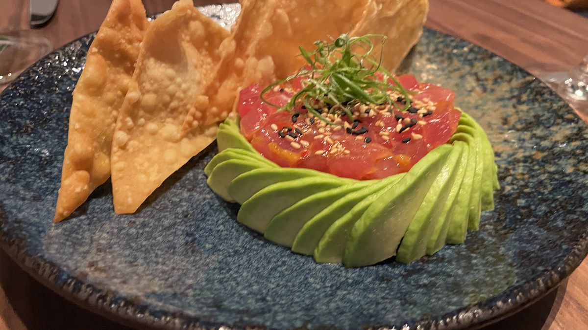 A plate of tuna tartare with crispy wontons and avocado.