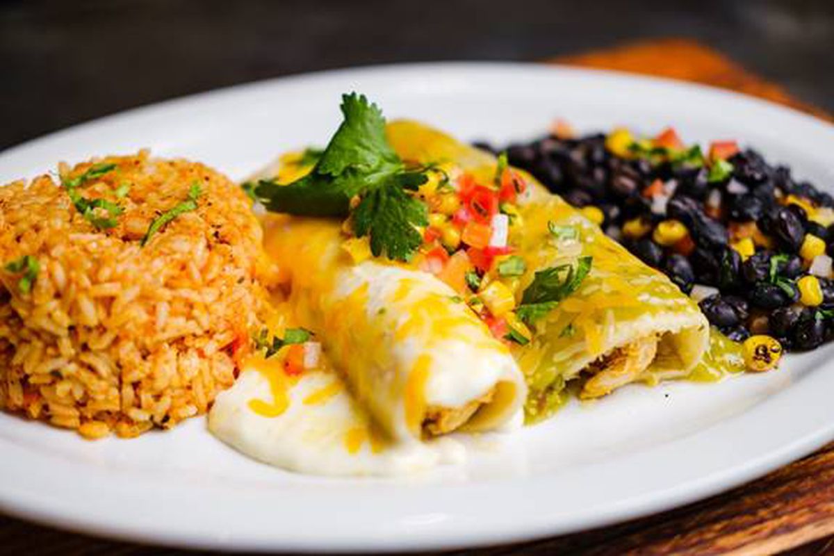 A pates of cheesy, gooey-looking enchiladas with black beans and Mexican-style rice.