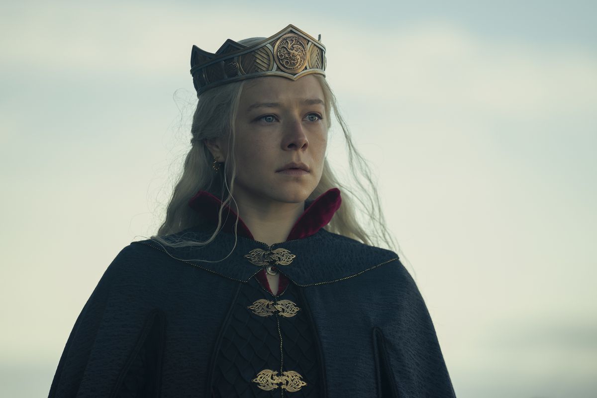 Emma D’Arcy in HBO’s House of the Dragon as Rhaenyra Targaryen stands in a cloak with a golden crown on her head