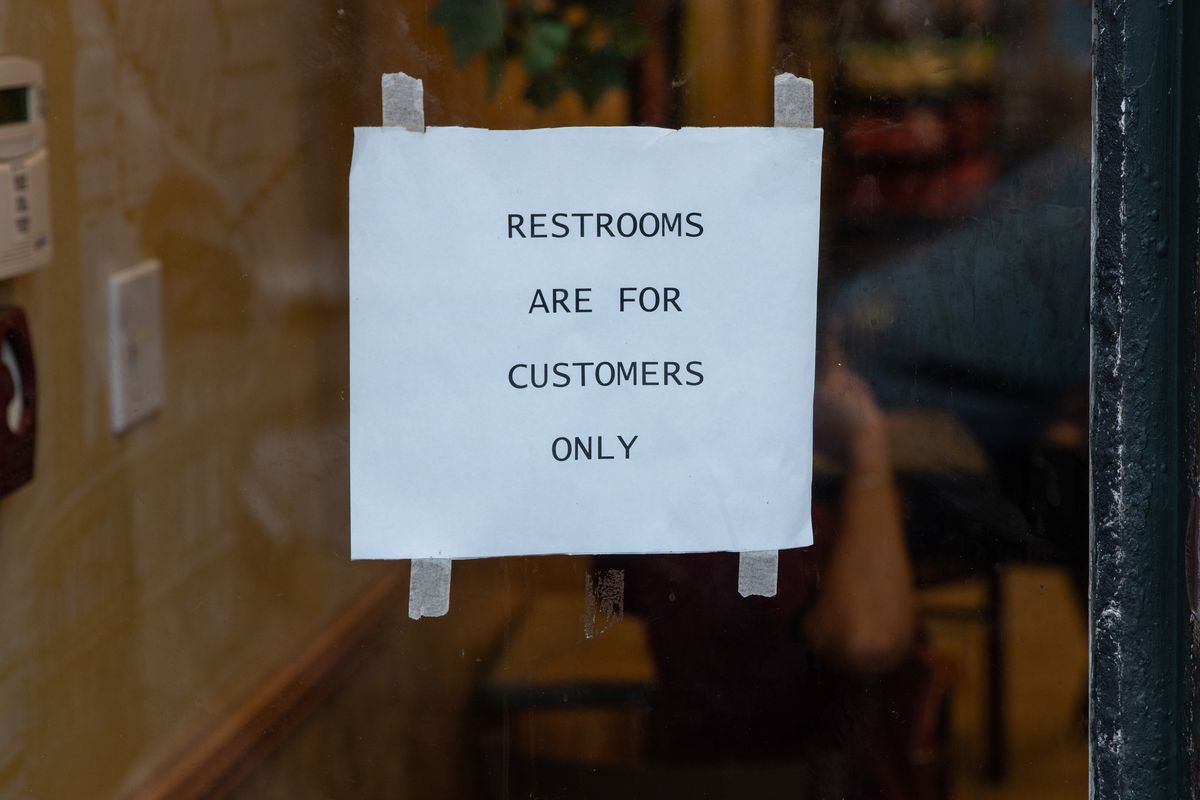 A paper sign taped to a window that reads “Restrooms are for customers only”.