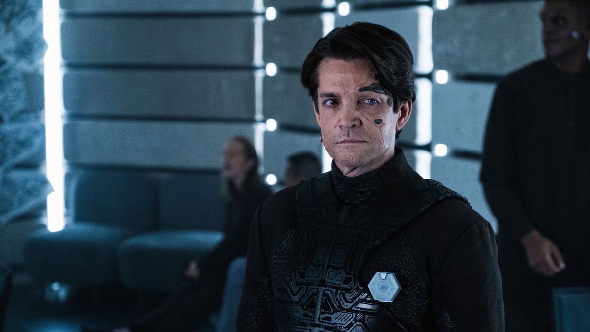 Hugh, a reclaimed Borg dressed in black and bearing metallic face inserts, looks offscreen in Star Trek: Picard.
