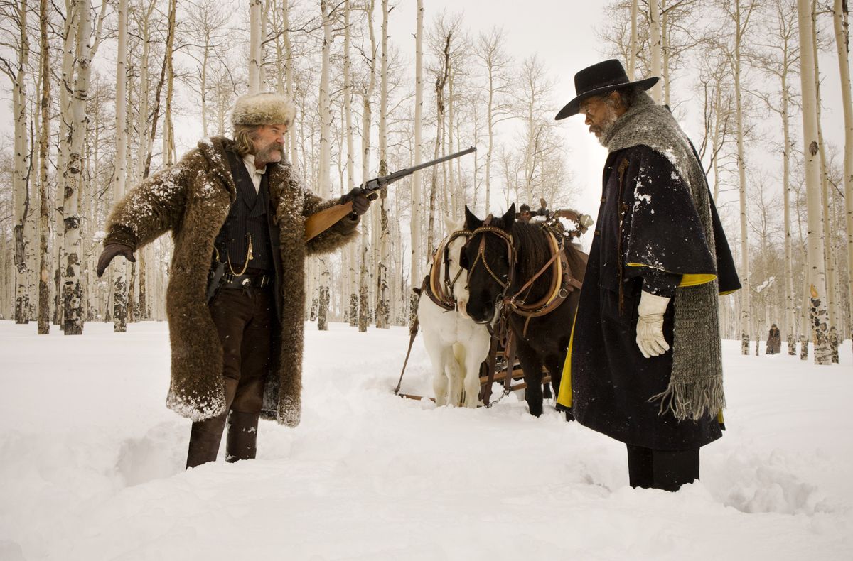 John Ruth (Kurt Russell) and Marquis Warren (Samuel L. Jackson) confront each other in a snowy field, with two horses looking on, in The Hateful Eight