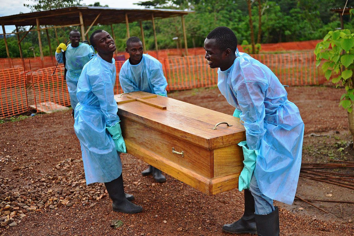 Sierra Leone government burial team members wearing protective clothing carry the coffin of Dr Modupeh Cole, Sierra Leone's second senior physician to die of Ebola.
