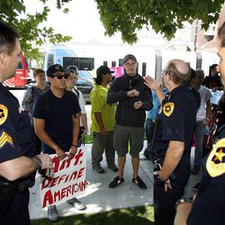 Salt Lake City police officers talk with a coalition of activists as they protest outside the Grand America Hotel. This is during the Mitt Romney visit to Salt Lake City, Tuesday, Sept. 18, 2012. 