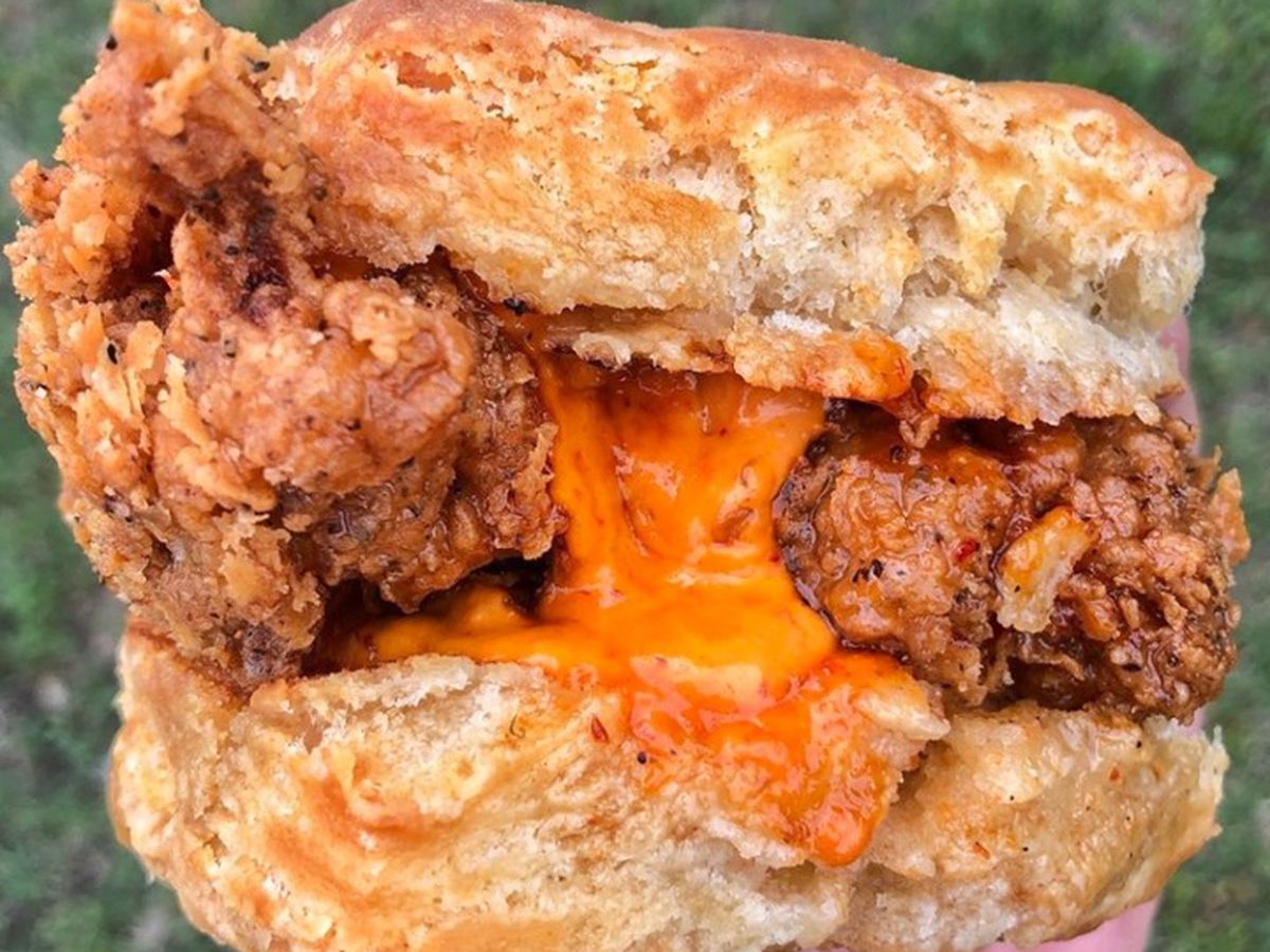 A fried chicken sandwich in between biscuit slices with melty yellow cheese.