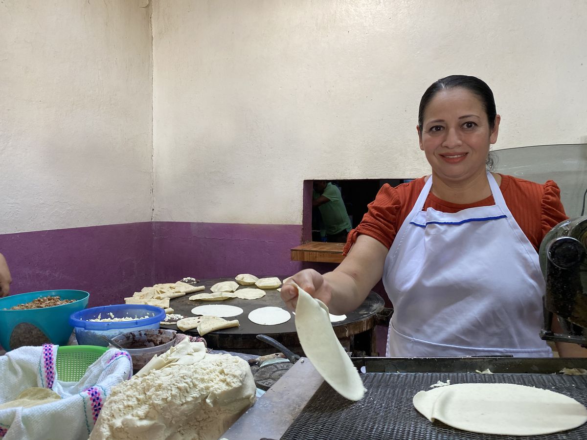 A chef places tortillas on a comal